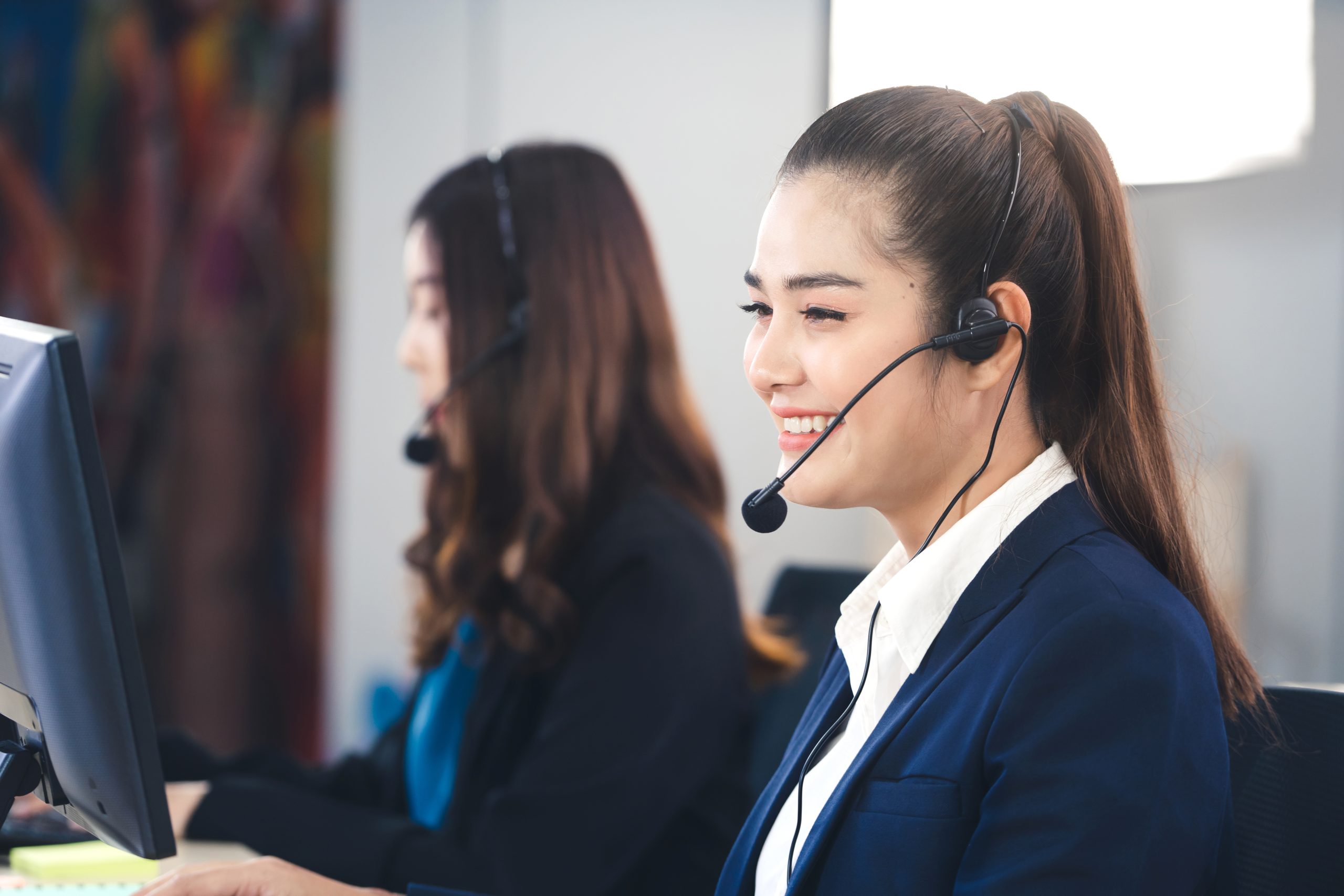 Customer call center service care concept. Positive smile young business staff asian woman using headphone and computer for support and organize as a teamwork in office.